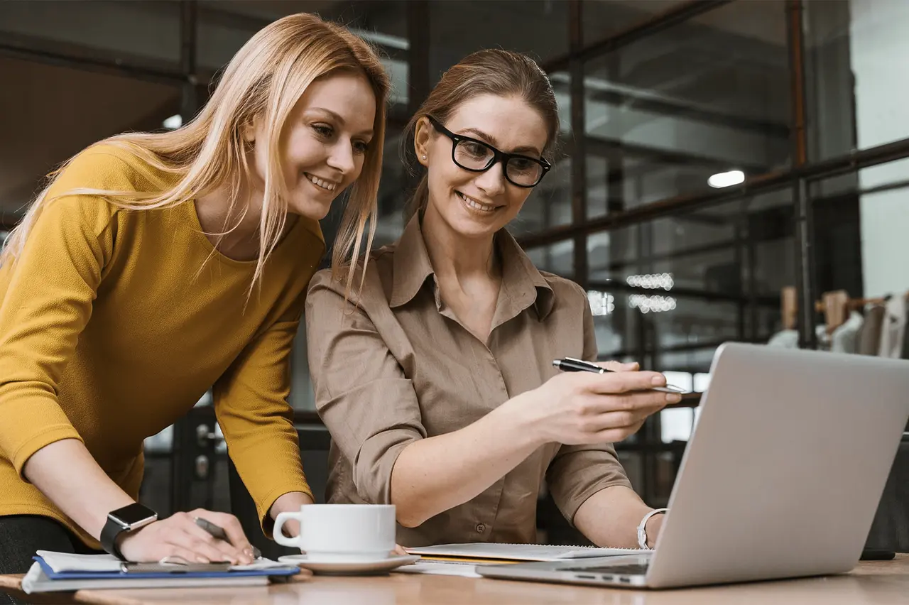 Female office colleagues looking at laptop