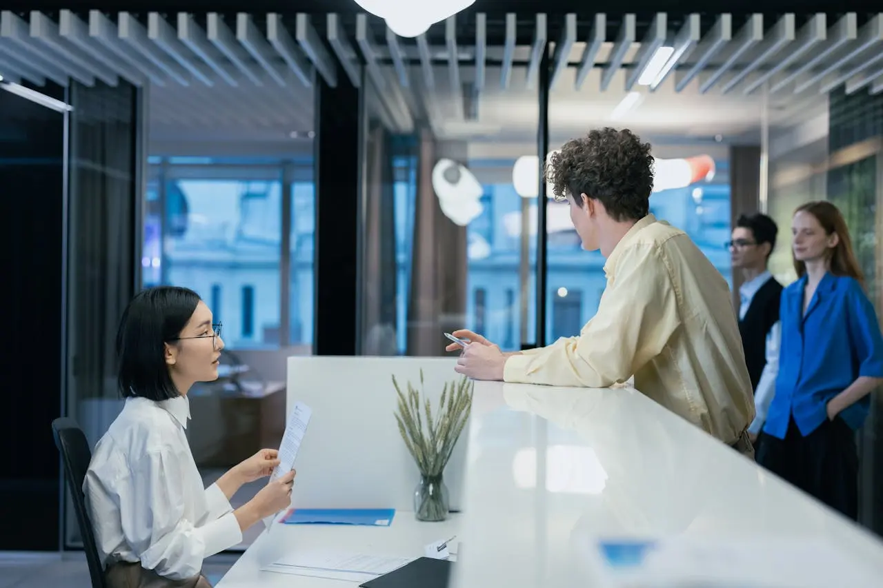 Female receptionist at desk talking to colleague